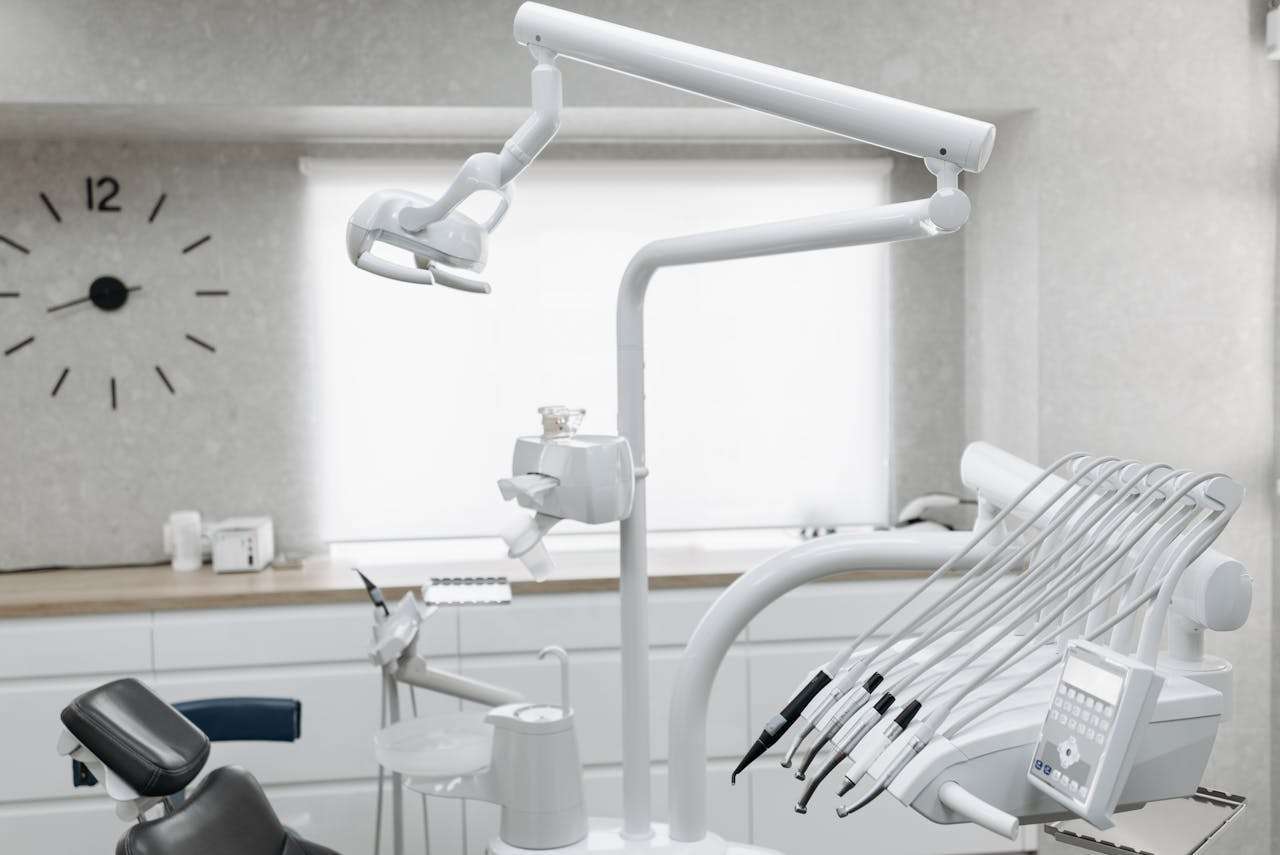 A close-up view of a pristine white dental operatory unit, featuring modern articulated lighting arms and a panel of professional dental instruments against a bright grey background.