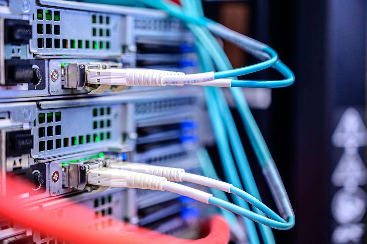 A macro close-up shot of thick light-blue ethernet fiber optic cables plugged into data ports on an active enterprise server rack switchboard with soft background lighting.